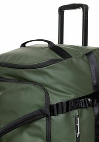 Groene duffeltas gemaakt van duurzaam materiaal, met zwarte riemen, een handvat, uitschuifbaar handvat en een ritssluiting aan de zijkant.