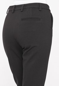 Black tailored pants with a smooth texture, featuring a narrow waistband, belt loops, and a single back pocket detail.