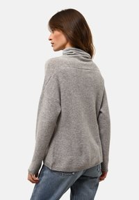 Harmaa, lämmin neulepaita, jossa on korkea kaulus, rento malli ja pudotetut olkaimet. Varustettu ribatut hihansuissa ja hieman pidemmässä takahännässä.