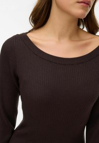 Smeđi rebrasti džemper s širokim izrezom i dugim rukavima, s teksturiranom površinom i krojem koji prianja uz tijelo.