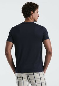 Navyblauwe t-shirt met korte mouwen en een ronde hals, met een gladde textuur en een getailleerd design, gecombineerd met licht geruite broek.