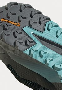 Suola di scarpa sportiva nera e verde petrolio con superficie texturizzata, profondi modelli di battistrada, sezioni rinforzate e logo Continental.