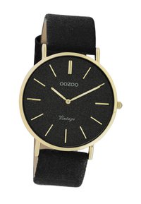 Montre OOZOO avec un cadran texturé noir, des index d'heure dorés et des aiguilles dorées, montée sur un bracelet en suede noir. Présente un design minimaliste.