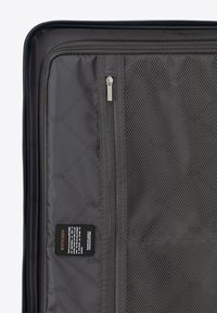 Schwarzes Kofferdeck mit einem Netzfach, einem Reißverschlussfach und einem Stoffetikett. Strukturiertes Material mit glatten Reißverschlüssen und Nähten.