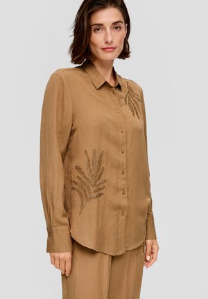 Chemise marron à manches longues, ornée de motifs de fougères brodés en fil métallique sur le devant. Tissu doux et texturé.
