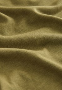 Tela de color verde oliva suave con una textura acanalada fina y pliegues naturales que crean sombras suaves.