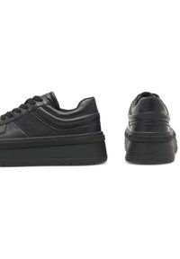 Adidași negri cu un superior din piele netedă, vârf rotund, talpă platformă groasă, accente texturate și șireturi plate pentru o fixare sigură.