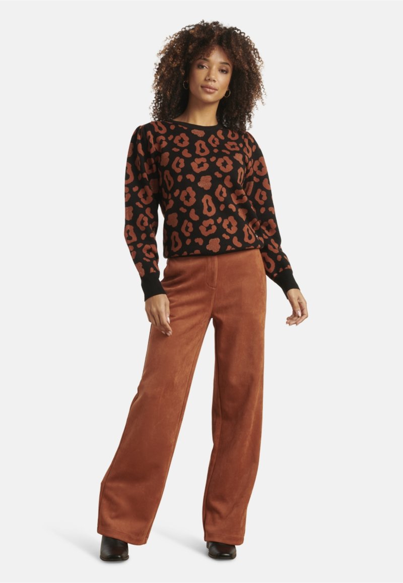 Zwart sweater met een roestkleurige luipaardprint, gecombineerd met roestkleurige wijde broekspijpen. De sweater heeft gebloemde mouwen en geribbelde manchetten.