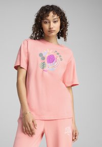 Pink cotton T-shirt featuring a colorful abstract graphic design with the word "PUMA." Short sleeves and a relaxed fit.