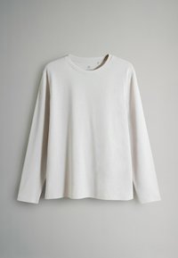 Ilgas rankovės balta marškinė su minkšta medžiaga, turinti apvalų kaklą ir laisvą sijoną. Paprastas dizainas be matomų raštų ar akcentų.