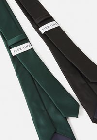 Deux cravates en vert foncé et noir, fabriquées en satin lisse. Chaque cravate porte une étiquette avec la mention "PIER ONE" pour identification.