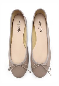 Bailarinas de piel en color topo con puntera redonda, ribete elástico y un lazo decorativo. El interior está forrado con un tejido de color amarillo claro.