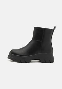 Stivaletti neri realizzati in pelle liscia, con una suola in gomma spessa caratterizzata da un motivo a zigzag e una linguetta sul retro.