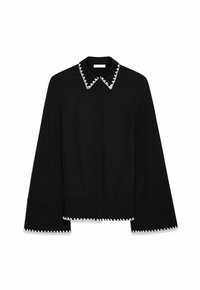 Black shirt with a pointed collar featuring white zigzag stitching. Long sleeves with flared cuffs and side pockets. Simple, clean design.