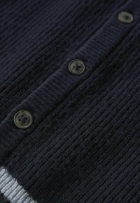 Navy knit cardigan featuring ribbed texture, four black buttons, and a grey striped accent at the hem. Soft, warm fabric composition.
