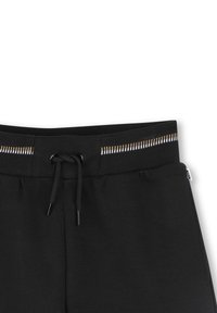 Pantaloni della tuta neri con un cinturino testurizzato e un cordoncino, dotati di un motivo a righe orizzontali in bianco e oro. Finitura in tessuto morbido.