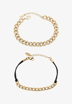 Dwie złote bransoletki łańcuszkowe, jedna z grubymi, teksturowanymi ogniwami i zapięciem typu karabińczyk, druga z gładkimi ogniwami na czarnym pasku z zapięciem.