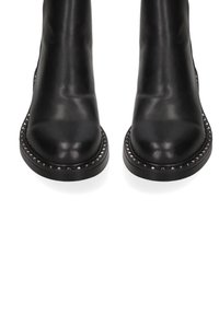 Stivali ankle in pelle nera con una texture liscia, punta arrotondata e accenti in borchie lungo la suola. Design elegante e minimalista.