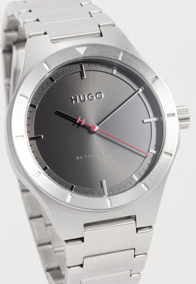 Montre-bracelet Silver Hugo avec cadran noir, index argentés et trotteuse rouge, équipée d'un bracelet à maillons en acier inoxydable.