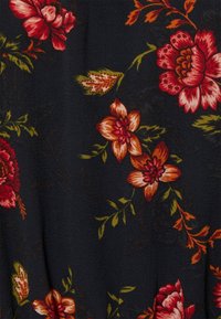 Tissu floral présentant de grandes fleurs rouges et orange avec des feuilles vertes sur un fond bleu marine foncé. Texture douce, détails de motifs intriqués.