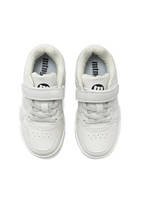 Zapatillas sintéticas blancas con una textura suave, diseño de cordones y tira de velcro. Presentan perforaciones en la punta y un logo en la lengüeta.