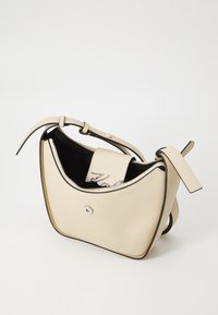 Sac à épaule en cuir crème, de forme courbée, intérieur noir, ferrures en argent et fermeture à pression. Présente un logo embossé sur le rabat.