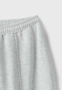 Close-up of light gray sweatpants showing elastic waistband and soft fabric texture.