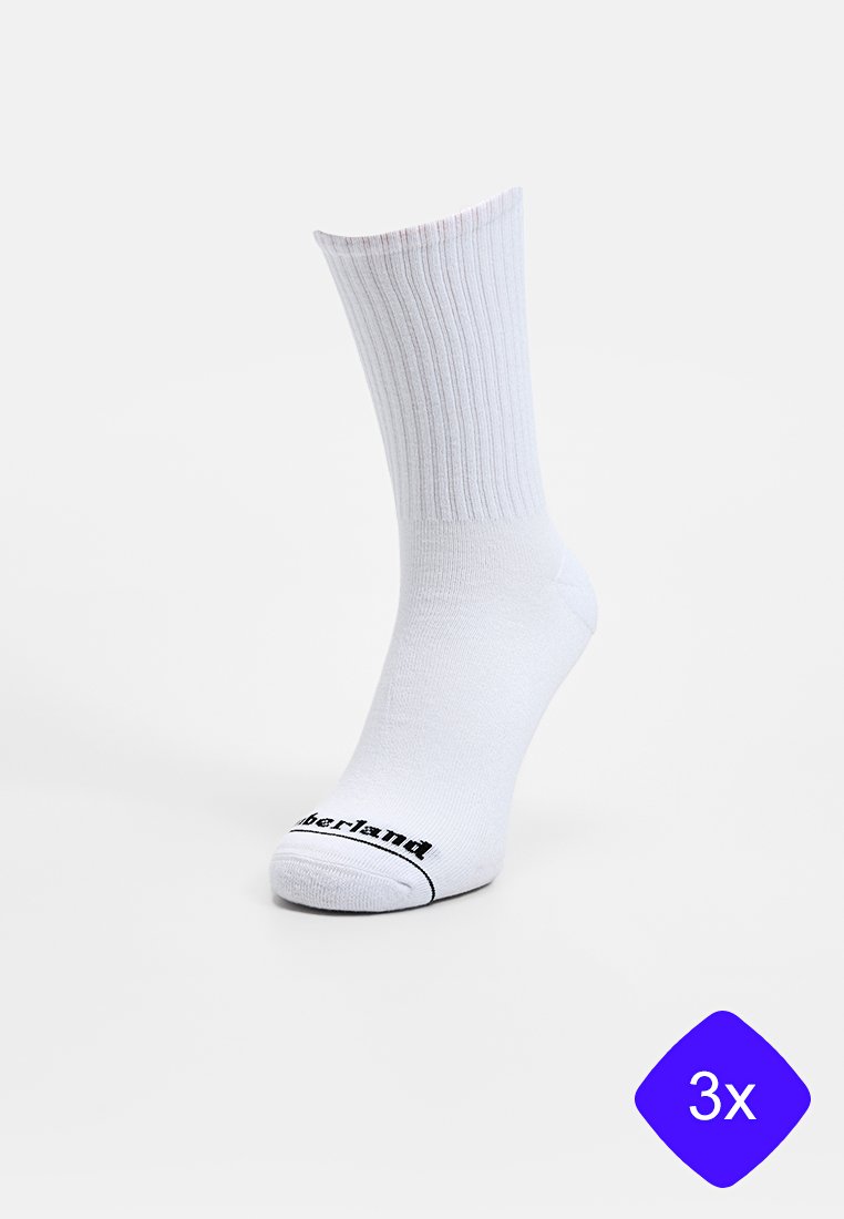 Chaussette blanche en coton à tige courte avec texture côtelée et logo noir sur le bout. Présentée à la verticale, indiquant un paquet de trois chaussettes.