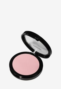 Poudre de blush compacte ronde avec un couvercle transparent, présentant une poudre lisse de couleur rose pâle. Étui noir mat avec un logo subtil.