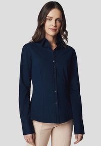 Granatowa, długi rękaw, koszula o dopasowanym kroju, z zapięciem na guziki i standardowym kołnierzykiem. Gładki materiał o drobnej fakturze i minimalnych akcentach.