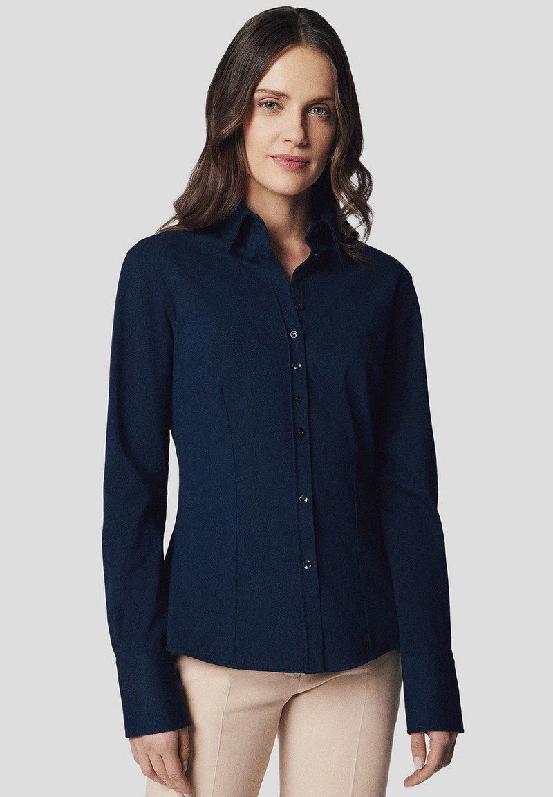 Granatowa, długi rękaw, koszula o dopasowanym kroju, z zapięciem na guziki i standardowym kołnierzykiem. Gładki materiał o drobnej fakturze i minimalnych akcentach.