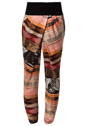 Femme portant une chemise en jean retroussée, un pantalon coloré à motifs, des talons noirs et tenant un grand sac cabas en cuir noir.