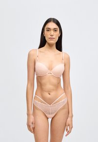 Csipkés rózsaszín melltartó merevítővel és hullámos szegéllyel, hozzáillő, geometriai mintás, vékony pántos tanga.