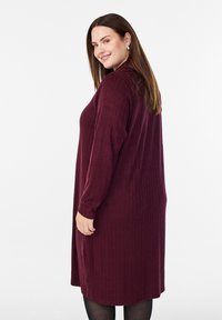 Burgundy långärmad klänning med ribbad struktur, knälång design, rund halsringning och sidslitsar för smidighet i rörelser.