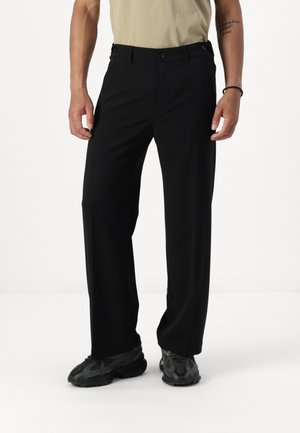 Pantalon noir ajusté avec une coupe droite, doté de deux poches avant, d'un devant plat et d'une texture de tissu lisse.