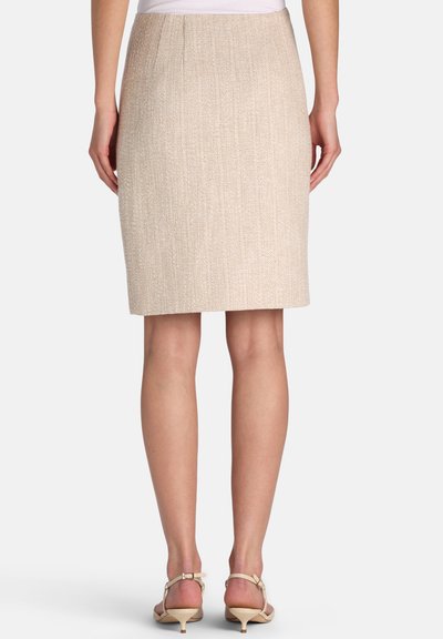 Beige knee-length textured skirt worn by person standing, paired with beige low-heeled sandals and white top, back view.