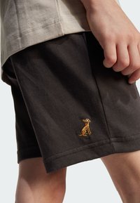Pantalones cortos marrón oscuro hechos de tela texturizada, con un pequeño diseño de perro bordado en el dobladillo. Los pantalones cortos tienen un corte recto y un ajuste relajado.