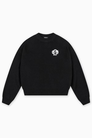 Svart ribbestrikket genser med rund hals. Har en hvit brodert logo på venstre side. Lange ermer og cropped passform.