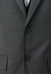 Grå blazer med teksturert stoff, strukturert design, enkeltspent stil og to svarte knapper. Inkluderer to frontlommer.