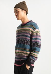 Knit sweater featuring multicolored horizontal stripes in blue, green, pink, and purple with textured patterns; ribbed neck and cuffs.