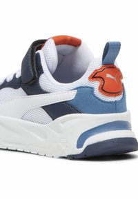 Baskets blanches avec un collier rembourré, des accents bleus, une tige en mesh texturé et un logo Puma rouge sur le talon. Système de fermeture à bande Velcro.