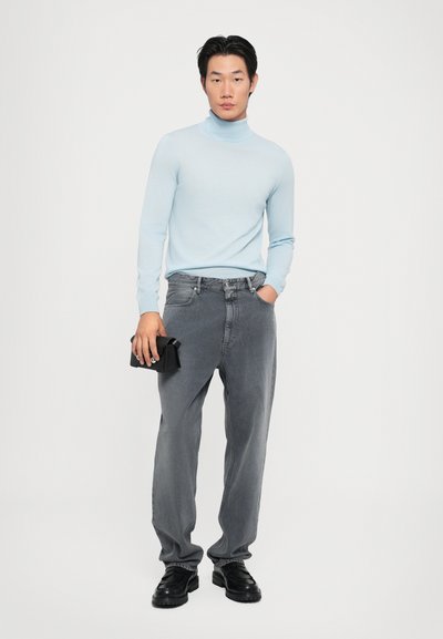 Svijetloplava turtleneck dukserica, sivi traperice, crna torba, crne cipele, ravni kroj, mekana tekstura i opušten dizajn.