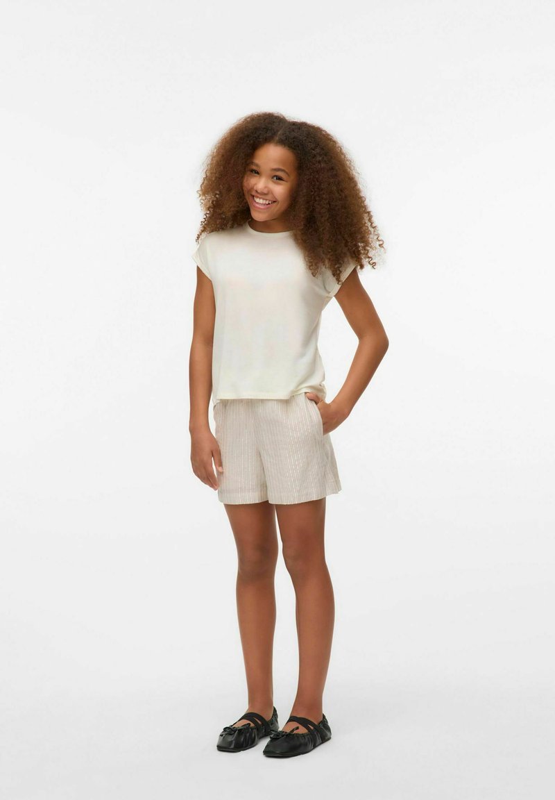 Top corto de manga corta beige claro y pantalones cortos a rayas beige. Zapatos planos negros. El tejido parece suave con un acabado ligeramente luminoso.