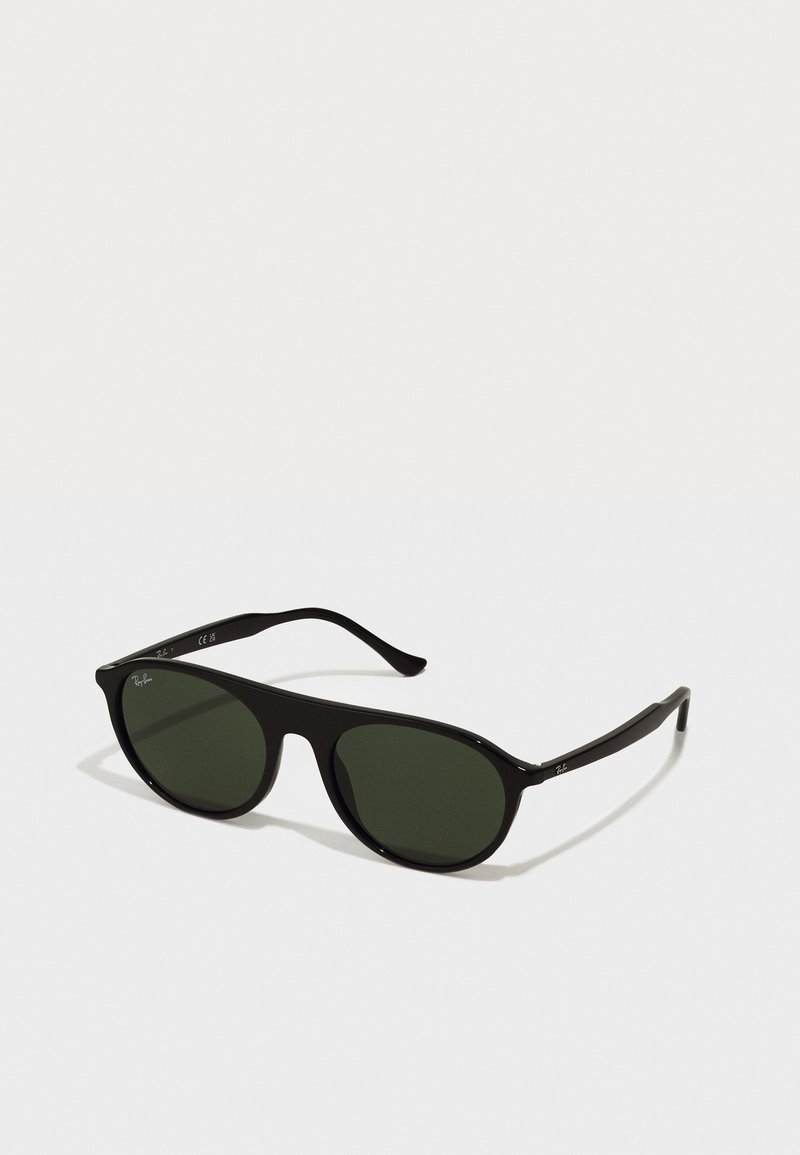 Ochelari de soare din plastic negru cu lentile rotunde, nuanță verde închis, brațe subțiri și logo argintiu pe un braț. Finisaj neted și design minimalist.