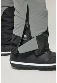 Stivali da neve neri e grigi con chiusura con zip, cinturino in Velcro e parte superiore testurizzata per una presa migliore, dotati di suola in gomma bianca per una buona aderenza.