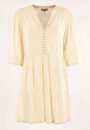 Robe à volants de couleur crème avec un col en V, des manches trois-quarts, et des clous argentés le long du col, des poignets et de l'ourlet.