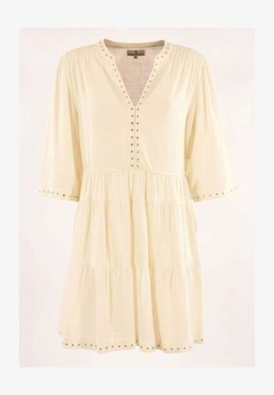 Robe à volants de couleur crème avec un col en V, des manches trois-quarts, et des clous argentés le long du col, des poignets et de l'ourlet.