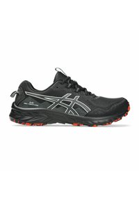 Zapatilla deportiva negra con parte superior sintética, que presenta acentos blancos y una suela texturizada con clavos de tracción rojos para mayor agarre. Diseño con cordones.