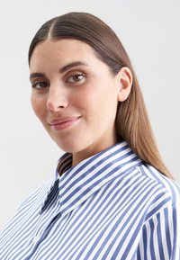 Hemd mit blauen und weißen vertikalen Streifen, aus Baumwolle, mit Knopfverschluss und glatter Oberfläche.