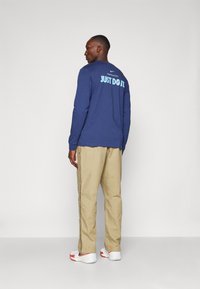 Nike Performance NBA PANT - Friluftsbukser - neutral olive/hyper crimson